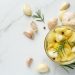 Garlic cloves with rosemary in a jar on marble background.