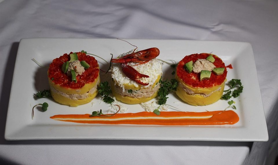 Peruvian causa with crab and avocado garnished with lobster.