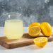 Glass of lemonade with fresh lemons on a wooden board.
