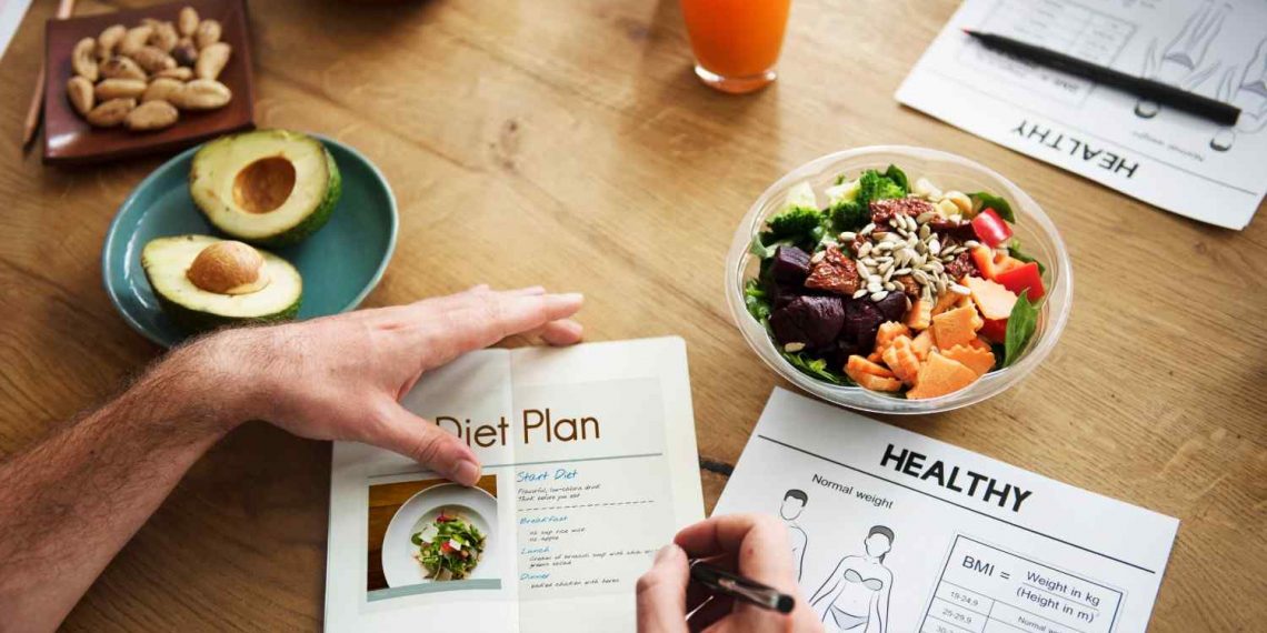 Person planning healthy diet with salad and avocado.