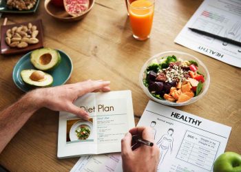 Person planning healthy diet with salad and avocado.