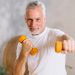 Senior man exercising with dumbbells indoors.