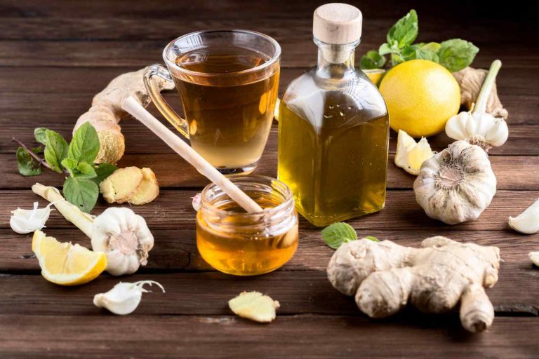 Herbal tea with ginger, garlic, lemon, and honey on a wooden table.