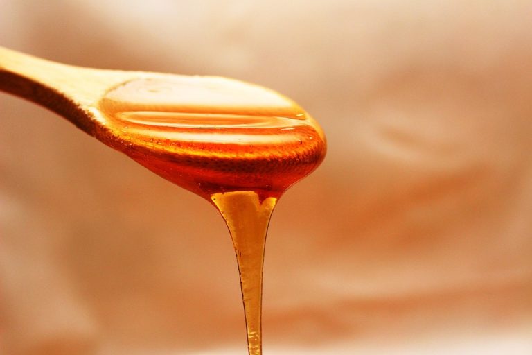 Golden honey dripping from a wooden spoon.