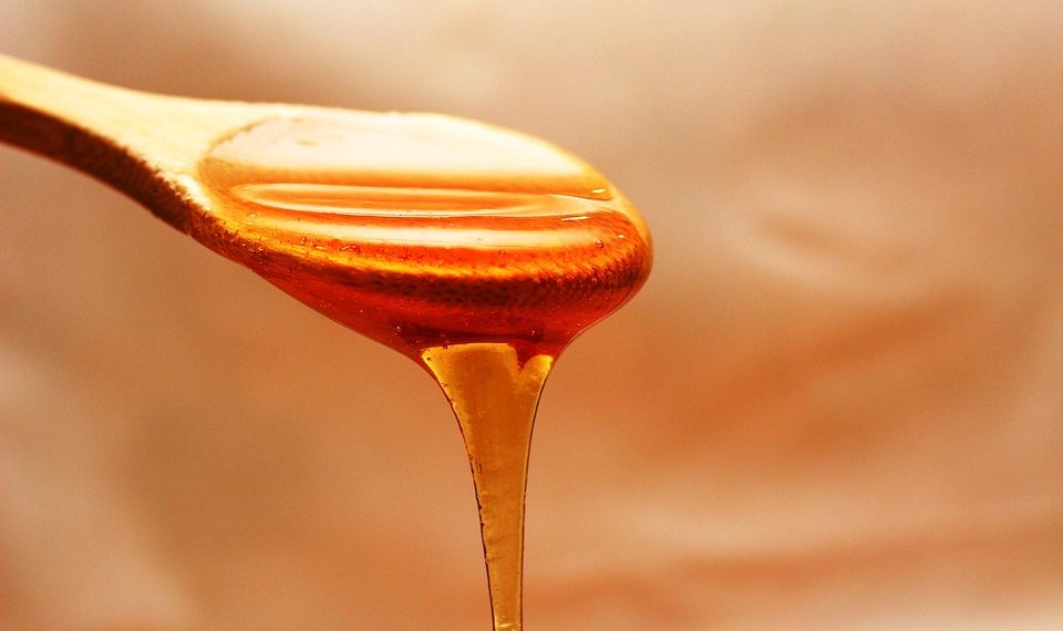 Golden honey dripping from a wooden spoon.