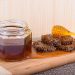 Honey jar and honeycomb on wooden board with dipper.