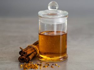 Cinnamon sticks and honey in a glass jar on gray background.