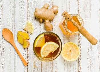 Ginger lemon tea with honey and fresh ginger slices on a wooden table.