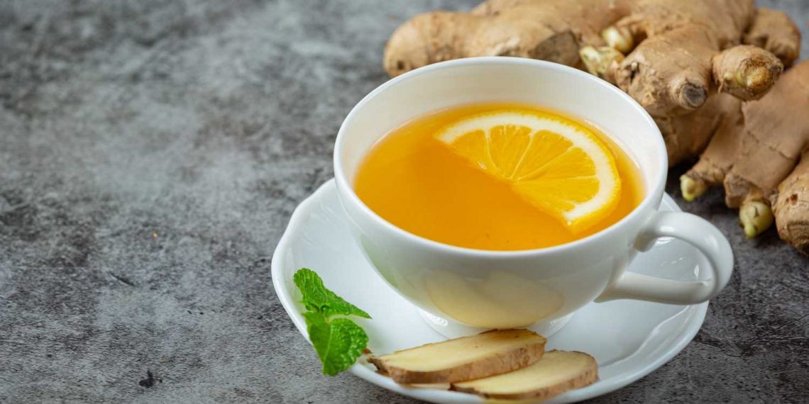 Ginger tea with lemon slice and fresh ginger root.