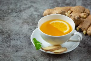 Ginger tea with lemon slice and fresh ginger root.