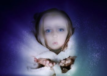 Child blowing magical sparkles in winter coat