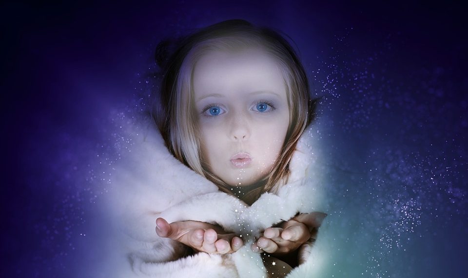 Child blowing magical sparkles in winter coat