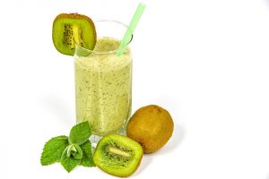 Kiwi smoothie in a glass with fresh kiwi and mint.