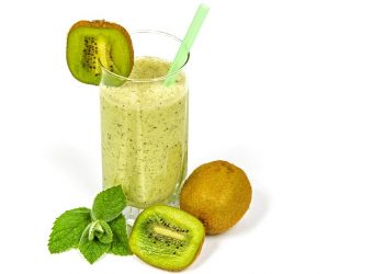 Kiwi smoothie in a glass with fresh kiwi and mint.