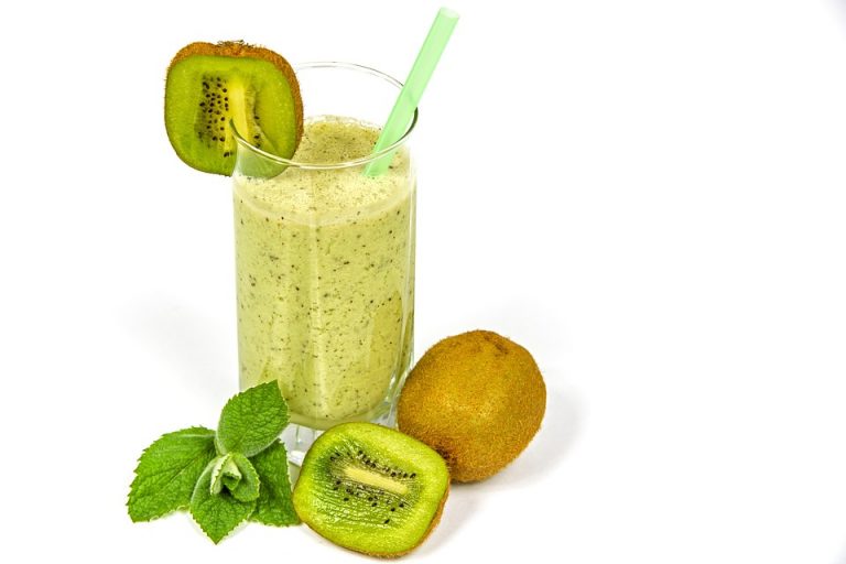 Kiwi smoothie in a glass with fresh kiwi and mint.