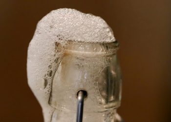Bubbles overflow on sealed glass bottle.