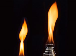 Lit flame on a lighter against a dark background.