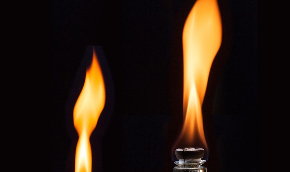 Lit flame on a lighter against a dark background.