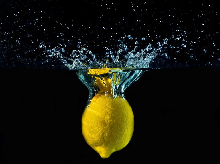 Lemon splashing into water creating ripples and bubbles.