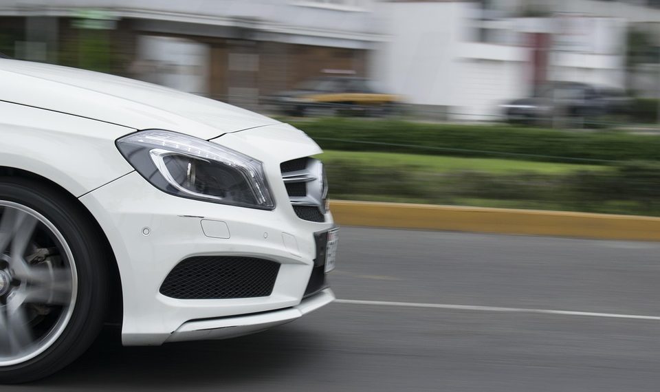 Speeding white car on a city street.
