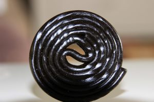 Black licorice wheel candy on a white background.