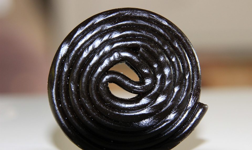 Black licorice wheel candy on a white background.