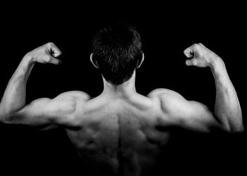 Man flexing back muscles in a bodybuilding pose.