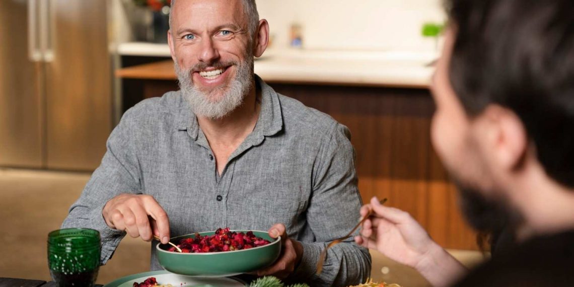 Man enjoying a meal with friends at the dinner table.