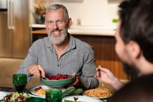 Man enjoying a meal with friends at the dinner table.