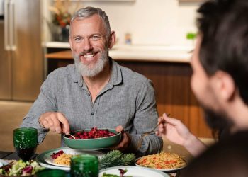 Man enjoying a meal with friends at the dinner table.