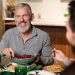 Man enjoying a meal with friends at the dinner table.