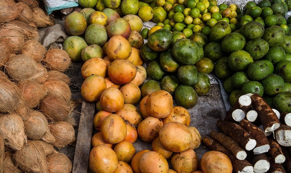 Tropical fruits and roots displayed in a vibrant market setting.