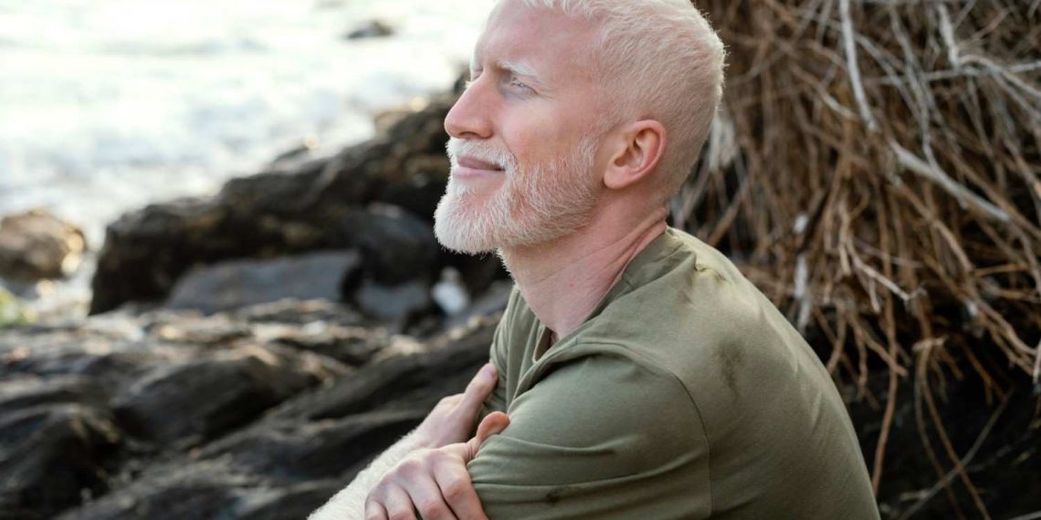 Man with closed eyes smiling by the seaside.