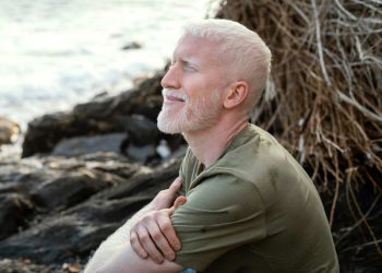 Man with closed eyes smiling by the seaside.