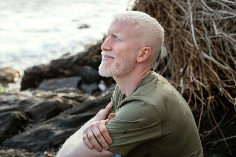 Man with closed eyes smiling by the seaside.