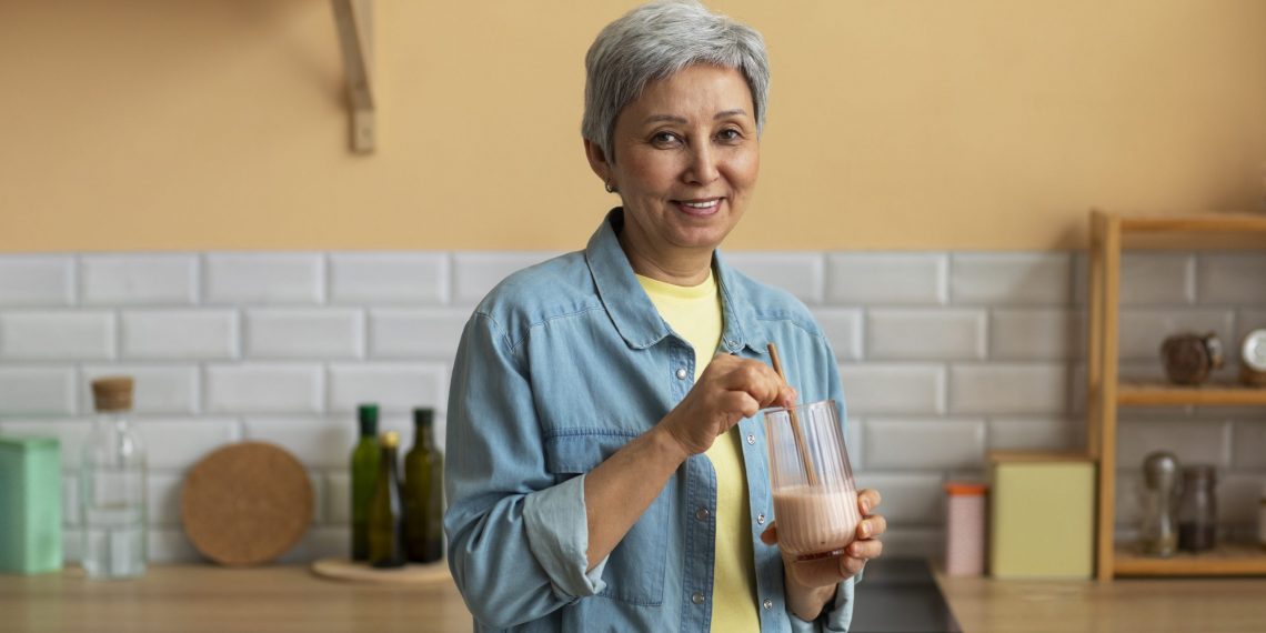 Senior woman preparing a smoothie in her kitchen.