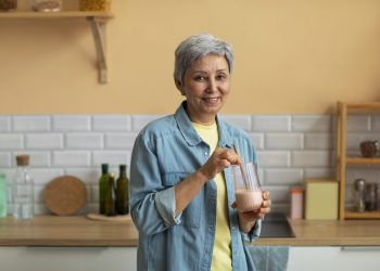Senior woman preparing a smoothie in her kitchen.