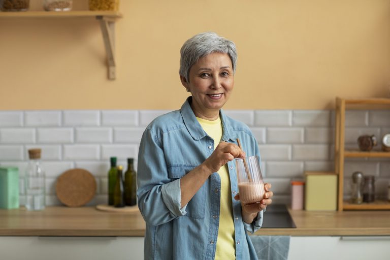 Senior woman preparing a smoothie in her kitchen.