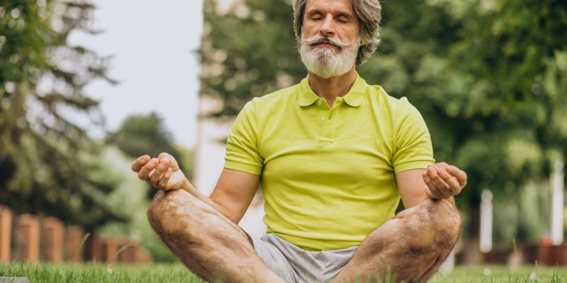 Senior man meditating in park, enjoying mindfulness.