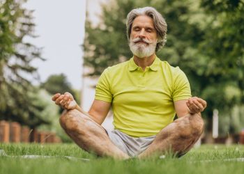 Senior man meditating in park, enjoying mindfulness.