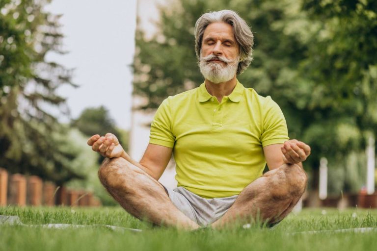 Senior man meditating in park, enjoying mindfulness.