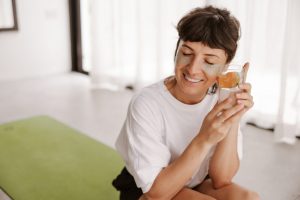 Woman smiling with eye patches holding citrus water.