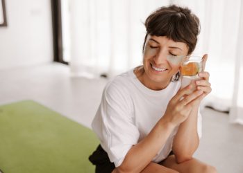 Woman smiling with eye patches holding citrus water.