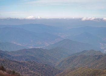 Mountain range view under blue sky with scattered clouds.