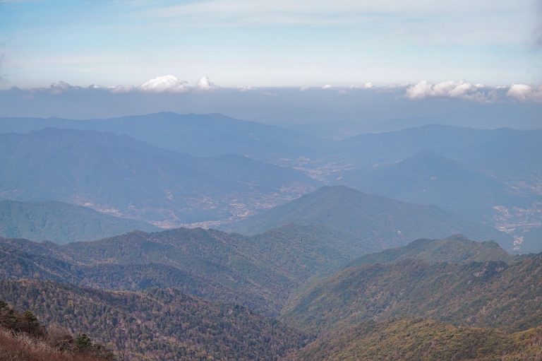 Mountain range view under blue sky with scattered clouds.