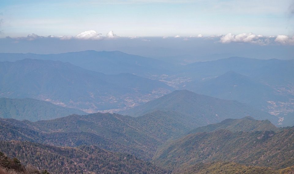 Mountain range view under blue sky with scattered clouds.