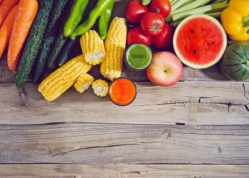 Fresh fruits and vegetables neatly arranged on a rustic wooden table.