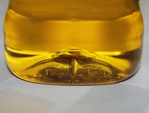 Yellow liquid in a plastic bottle on a white surface.