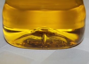 Yellow liquid in a plastic bottle on a white surface.