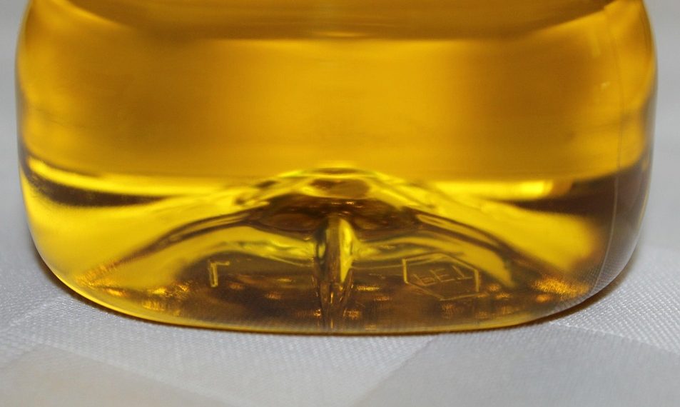 Yellow liquid in a plastic bottle on a white surface.